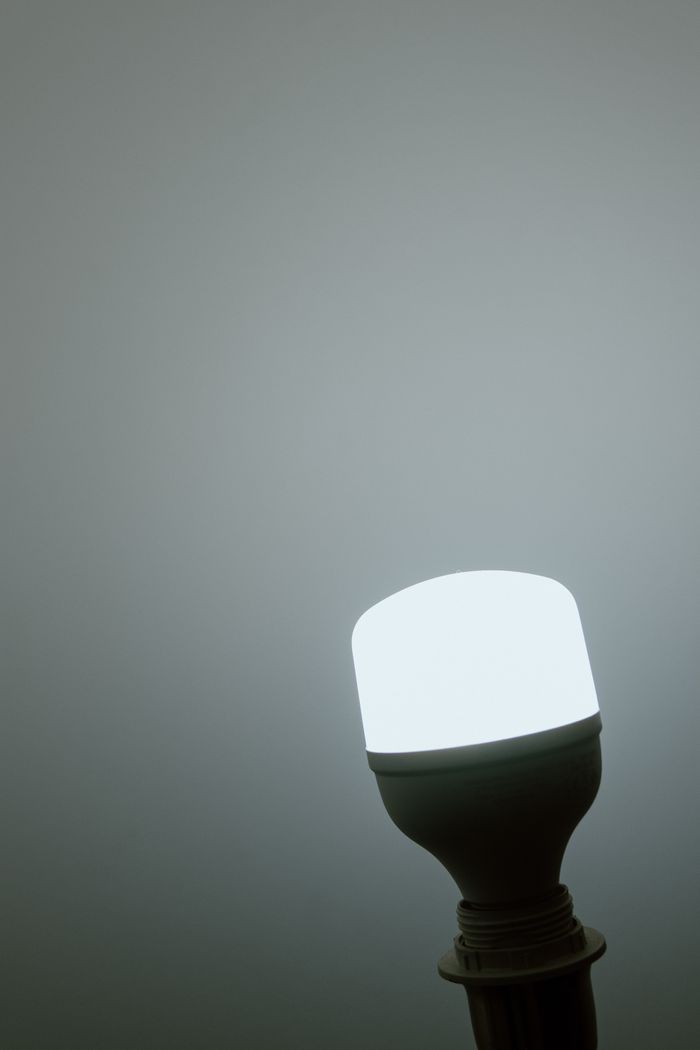 A glowing LED light bulb against a minimalist grey background, emphasizing simplicity and efficiency.